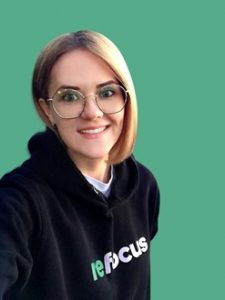 Blonde woman with glasses and a black sweatshirt posing for a portrait